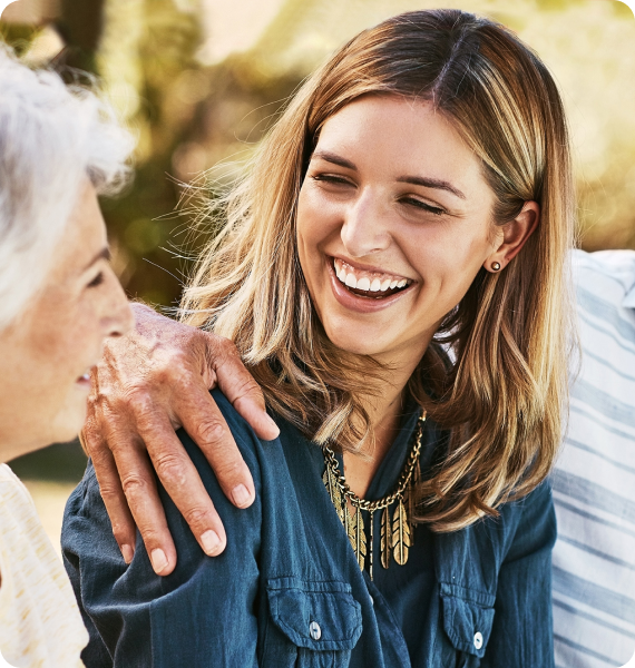 Two women smiling and laughing together outdoors
